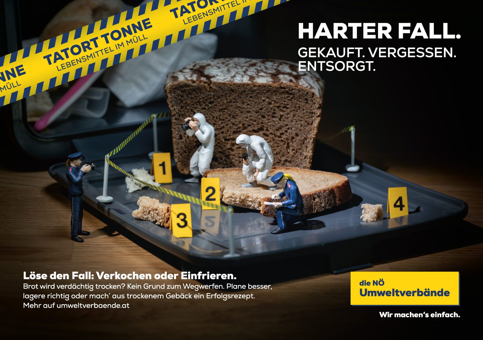 Miniaturpolizisten inspizieren den Tatort Tonne mit Brot und Geb&auml;ck.