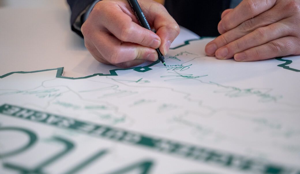 Auf dem Bild ist eine Nieder&ouml;sterreichkarte mit dem ReVital Logo zusehen sowie die diverse Unterschriften und eine Hand, die einen gr&uuml;nen Stift h&auml;lt und unterschreibt.
